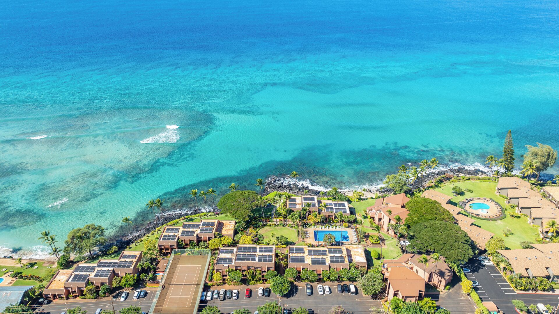 A resort with multiple buildings, a swimming pool, and a view of the ocean.