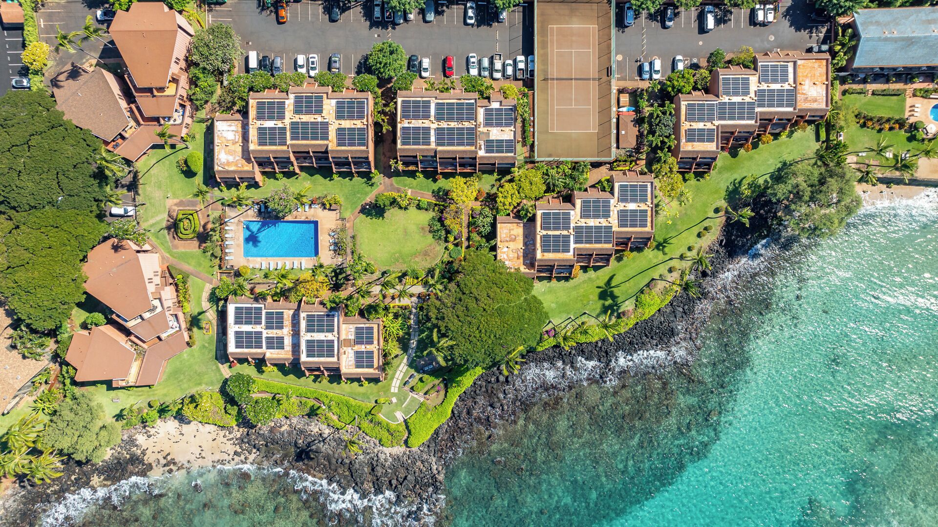 An aerial view of a coastal hotel with multiple buildings, a swimming pool, and a beach.