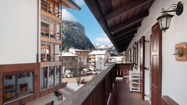 A balcony with wooden railings overlooking a snowy mountain village. - Apartment 'Giulia' with Mountain View, Shared Garden and Balcony (Canazei)