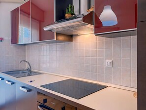 Une cuisine moderne équipée d’une cuisinière intégrée, d’un évier et d’un meuble avec une porte en verre.