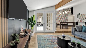 Een moderne woonkamer met een houten vloer, een blauw versierd vloerkleed, een grijze bank en een zwarte salontafel.