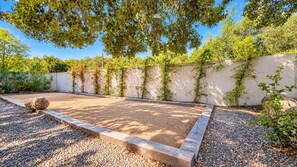 A garden with a gravel path, a wooden deck, and a wall with climbing plants.