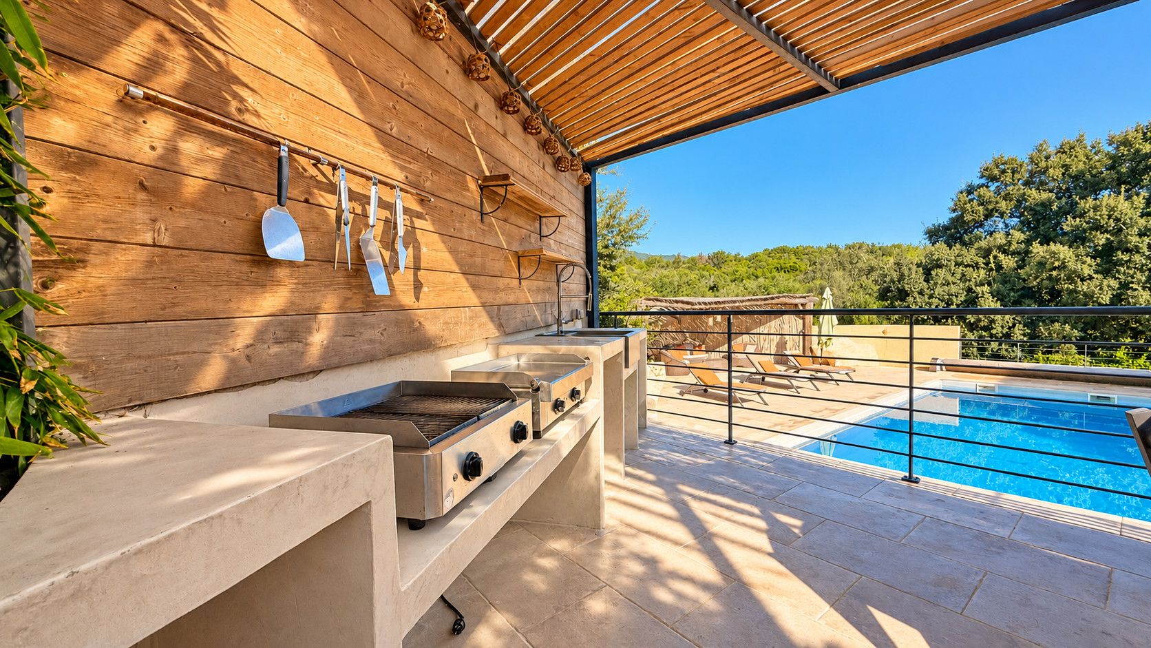 Un área de barbacoa al aire libre con piscina y sillas de descanso.