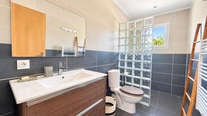 Une salle de bain moderne avec un grand lavabo, des toilettes et une fenêtre donnant sur un beau paysage.