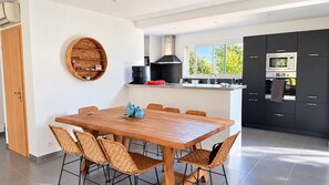 A modern kitchen with a large island, black cabinets, and a built-in microwave.