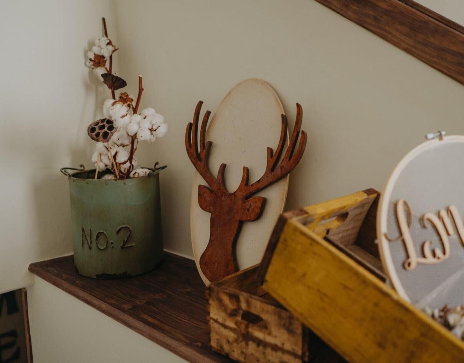 A rustic wooden shelf with a metal container labeled 'NO.2,' a wooden deer head decoration, and a box with a nameplate.