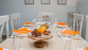 A dining table set with orange napkins, clear glassware, and a centerpiece of nuts and a pumpkin.