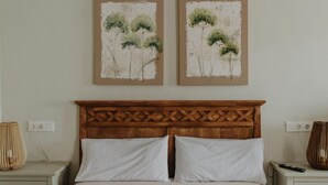 A bedroom with a wooden headboard, two white pillows, a bed, and two nightstands with lamps and a remote control.