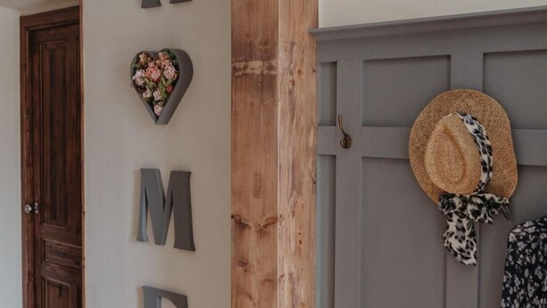 A room with a wooden door, a gray wall with large letters spelling 'HOME,' and a hat hanging on the door.