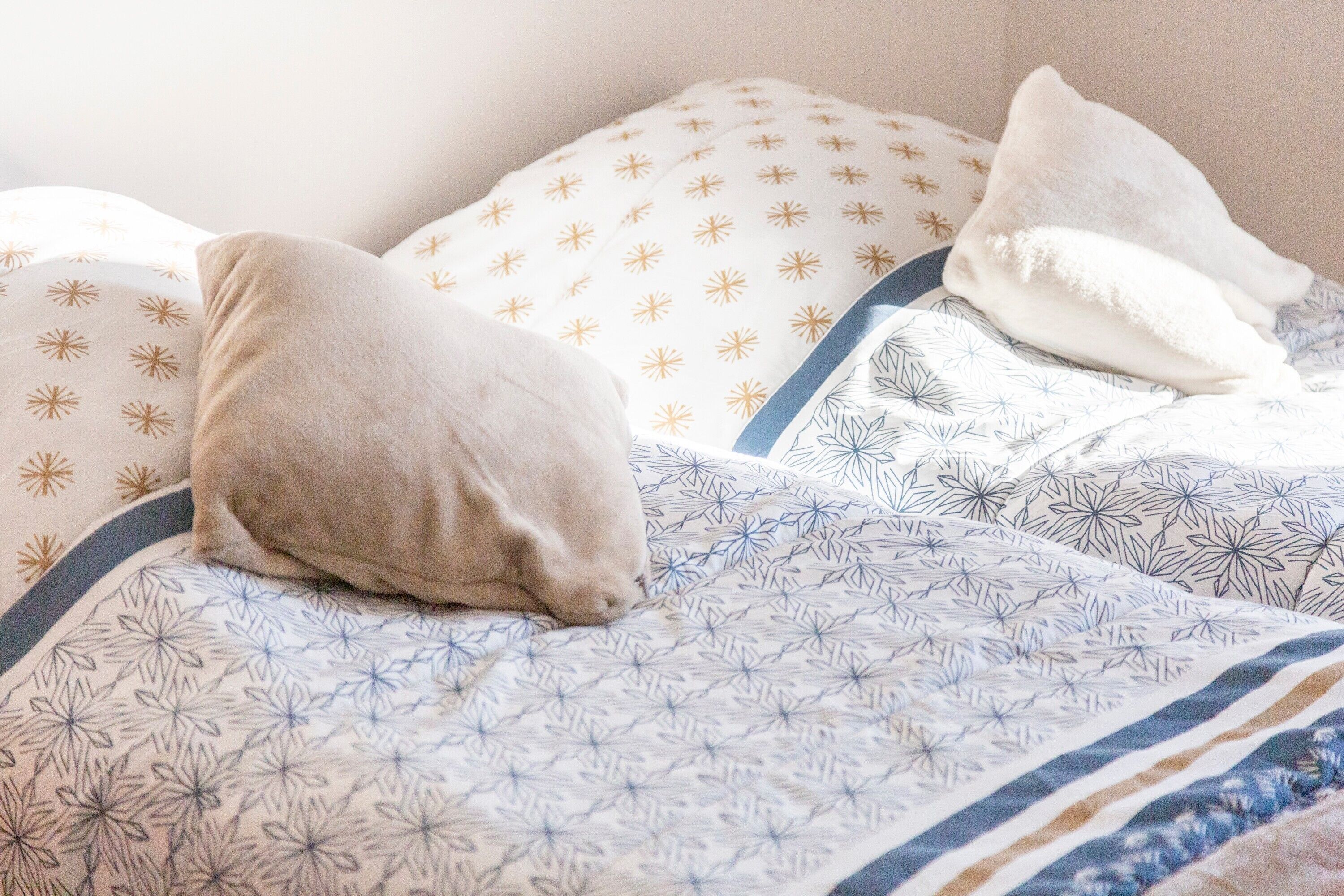 Ein Bett mit gemusterten Bettwaren und Kissen.