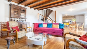 A spacious living area with a wooden ceiling, a glass coffee table, a red sofa, and a wooden cabinet. - Holiday Home 'Les Hirondelles' with Private Terrace, Private Garden and Wi-Fi (Mellac)