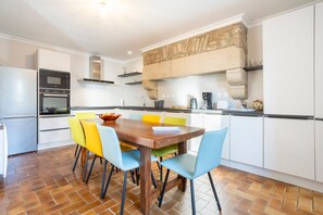 A modern kitchen with a dining table, chairs, and a stone accent wall.