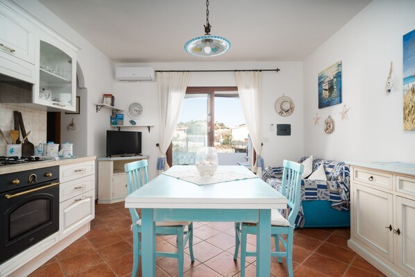 A kitchen with white cabinets, a dining table, and a TV.