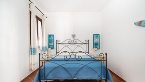 Ein Bett mit blauer Bettdecke, einem Metall-Kopfschild und einer Wanddekoration in Herzform.