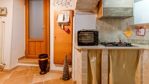 A kitchen with a microwave, a stove, a wooden door, a small Christmas tree, and a tiled backsplash.