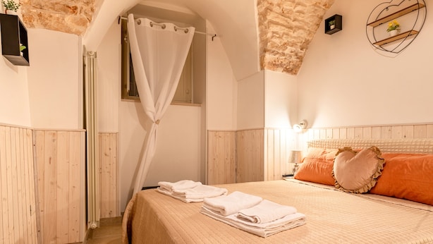 A bedroom with a bed, a window, a curtain, and a wall-mounted shelf.