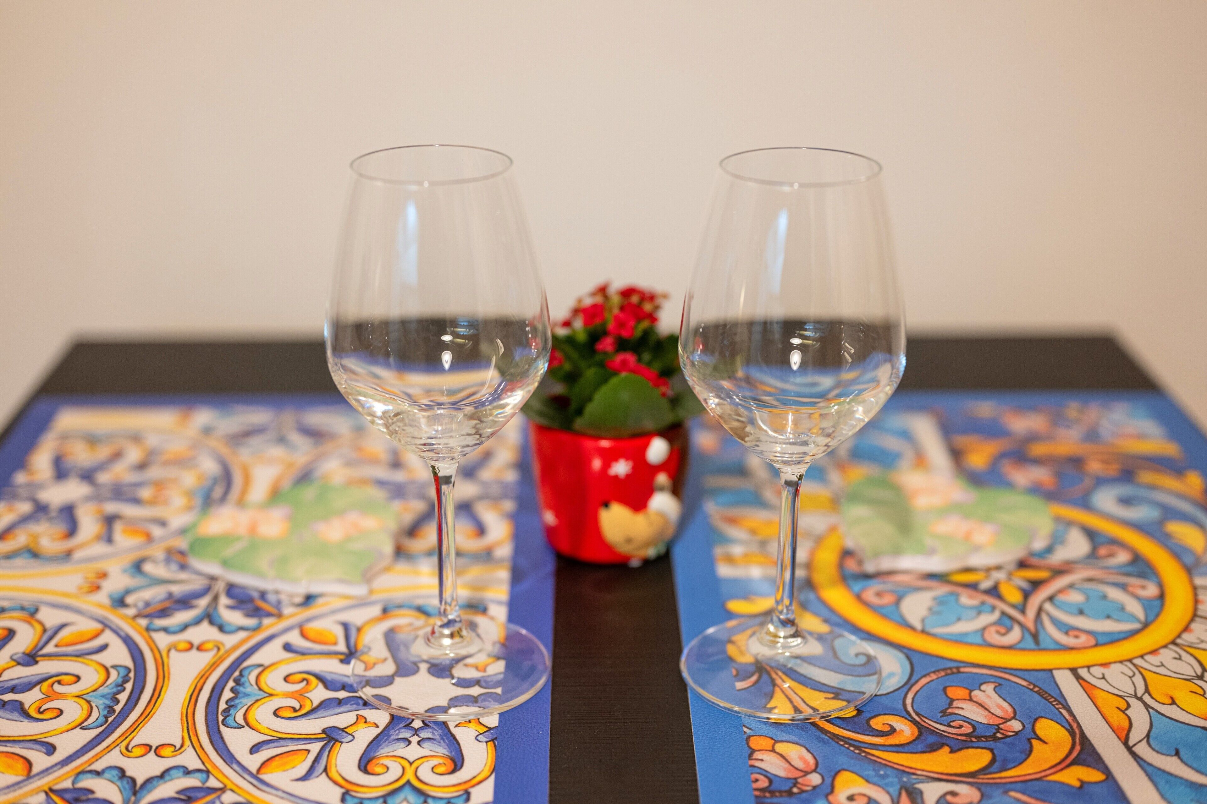 Two empty wine glasses on a table with a colorful patterned tablecloth.