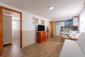 A living room with a sofa, TV, wooden cabinet, and a dining area with chairs and a table. - Apartment 'Noria 2' with Air Conditioning (nijar)