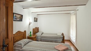 Un dormitorio con dos camas individuales, un armario de madera, una mesita de noche con una lámpara y un cuadro en la pared.