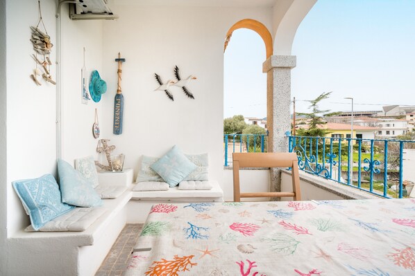 A balcony with a white bench, decorative wall art, and a view of the neighborhood.