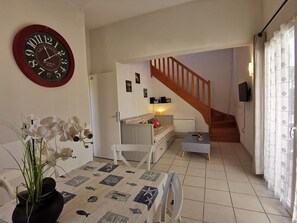 Un saló amb taula de dinar, rellotge, escala i llit.