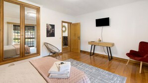 Ein Schlafzimmer mit einem Bett, einem Schreibtisch, einem Fernseher, einem Sessel und einem Kleiderschrank.