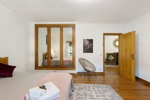 Ein Schlafzimmer mit Bett, Stuhl, Kleiderschrank und einer Tür zu einem anderen Raum.