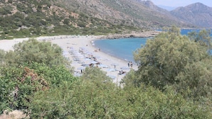 A beach with sun loungers and umbrellas, surrounded by trees and mountains. - Cottage 'Olive Tree   4' with Sea View, Private Terrace and Wi-Fi (Paleochora-Crete)