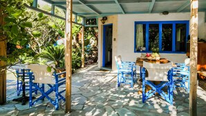 An outdoor patio with blue chairs and a table, surrounded by greenery and a stone floor. - Cottage 'Olive Tree   4' with Sea View, Private Terrace and Wi-Fi (Paleochora-Crete)