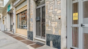 A building with a stone facade, a metal gate, and a yellow warning sign. - GuestHost - Comfy APT in Santa Rita District (Torino)