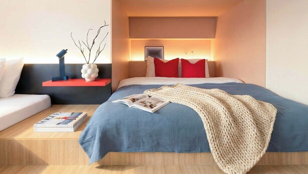 Ein modernes Schlafzimmer mit Bett, Nachttischen, einer Leselampe und einer dekorativen Vase.
