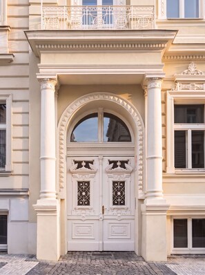 A double door with intricate ironwork, flanked by columns, and a balcony above. - TurnKey | Wenceslas square Two Level Apartment XI (Praha 1)