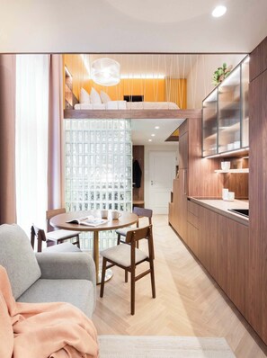 A modern interior with a dining area, kitchen, and a loft bedroom. - TurnKey | Wenceslas square Two Level Apartment XI (Praha 1)