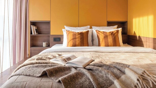 Une chambre à coucher moderne avec un lit, des oreillers, un livre et une table de chevet.