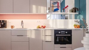 A modern kitchen with a coffee machine, sink, and oven. There is a fruit bowl on the counter and a vase with flowers on the right. - TurnKey | Wenceslas square Apartment II (Praha 1)