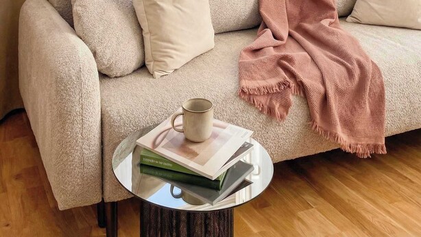 A cozy living room with a sofa, a coffee table, and a view of a cityscape through a window. - TurnKey | Wenceslas square Apartment II (Praha 1)