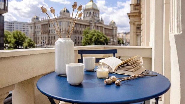 A balcony with a table set with a book, a candle, and a vase with dried flowers. - TurnKey | Wenceslas square Apartment w/ balcony V (Praha 1)