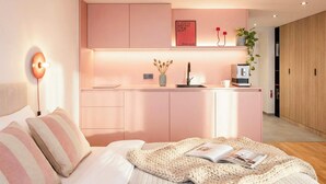 A modern bedroom with a bed, bedside table, and a small kitchenette area. - TurnKey | Wenceslas square Apartment w/ balcony V (Praha 1)