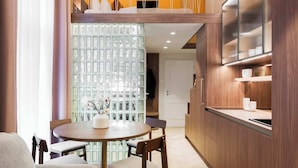 A modern kitchen with wooden cabinets, a dining area with a round table and chairs, and a cozy seating area with a sofa and a throw blanket. - TurnKey| Wenceslas square Two Level Apartment XIII (Praha 1)