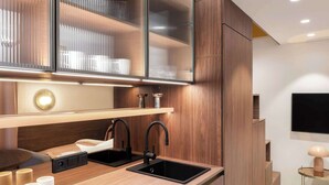 A modern kitchen with wooden cabinetry, a black sink, and a built-in stove. - TurnKey| Wenceslas square Two Level Apartment XIII (Praha 1)