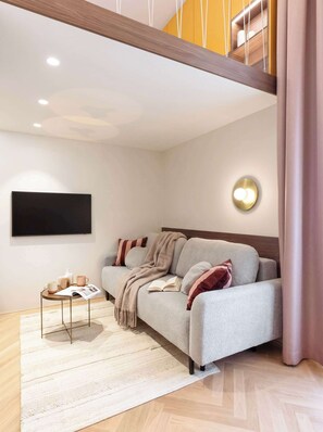 A modern living room with a sofa, a coffee table, and a flat-screen TV mounted on the wall.