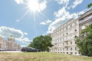 Un bâtiment à l’architecture classique, un parking et un ciel dégagé.