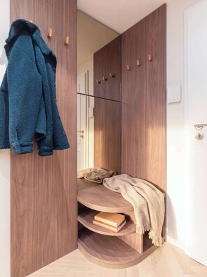 Een kamer met een kledingkast, een bank met een deken en een jas aan de muur.