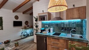 Une cuisine avec des poutres en bois, un luminaire suspendu, un revêtement mural en carreaux et un lave-vaisselle encastré.