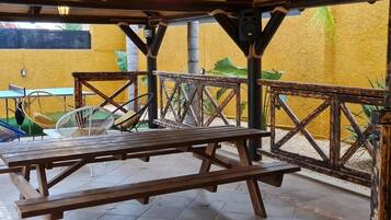 An outdoor patio with wooden benches and a fan.