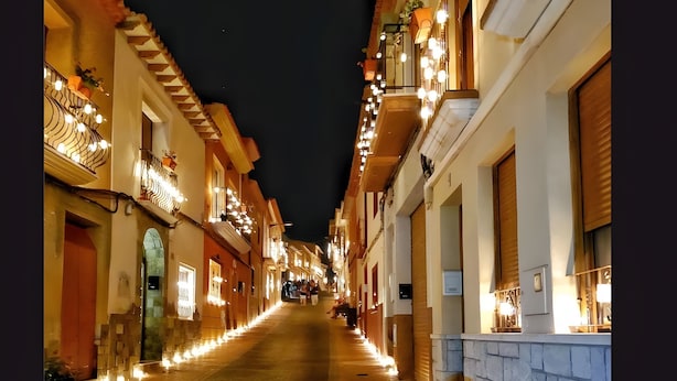 A narrow street with buildings on both sides, illuminated by warm lighting.