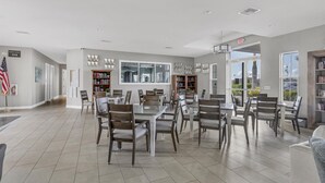A spacious dining area with a high ceiling, multiple tables, and chairs. There are bookshelves along the walls and a large window providing natural light. - Punta Gorda 2 Bedroom Home Dog Friendly! (Punta Gorda)