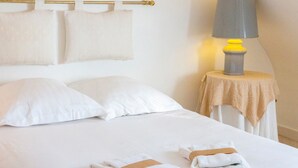 A hotel room with a bed, pillows, a nightstand with a lamp, and towels. - Ty Mamm – 5 min from Beach – 3 Bedrooms – Sleeps 6 (Guilvinec)
