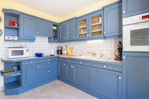 Une cuisine avec des meubles de couleur bleue, un four à micro-ondes, une machine à café et un évier.