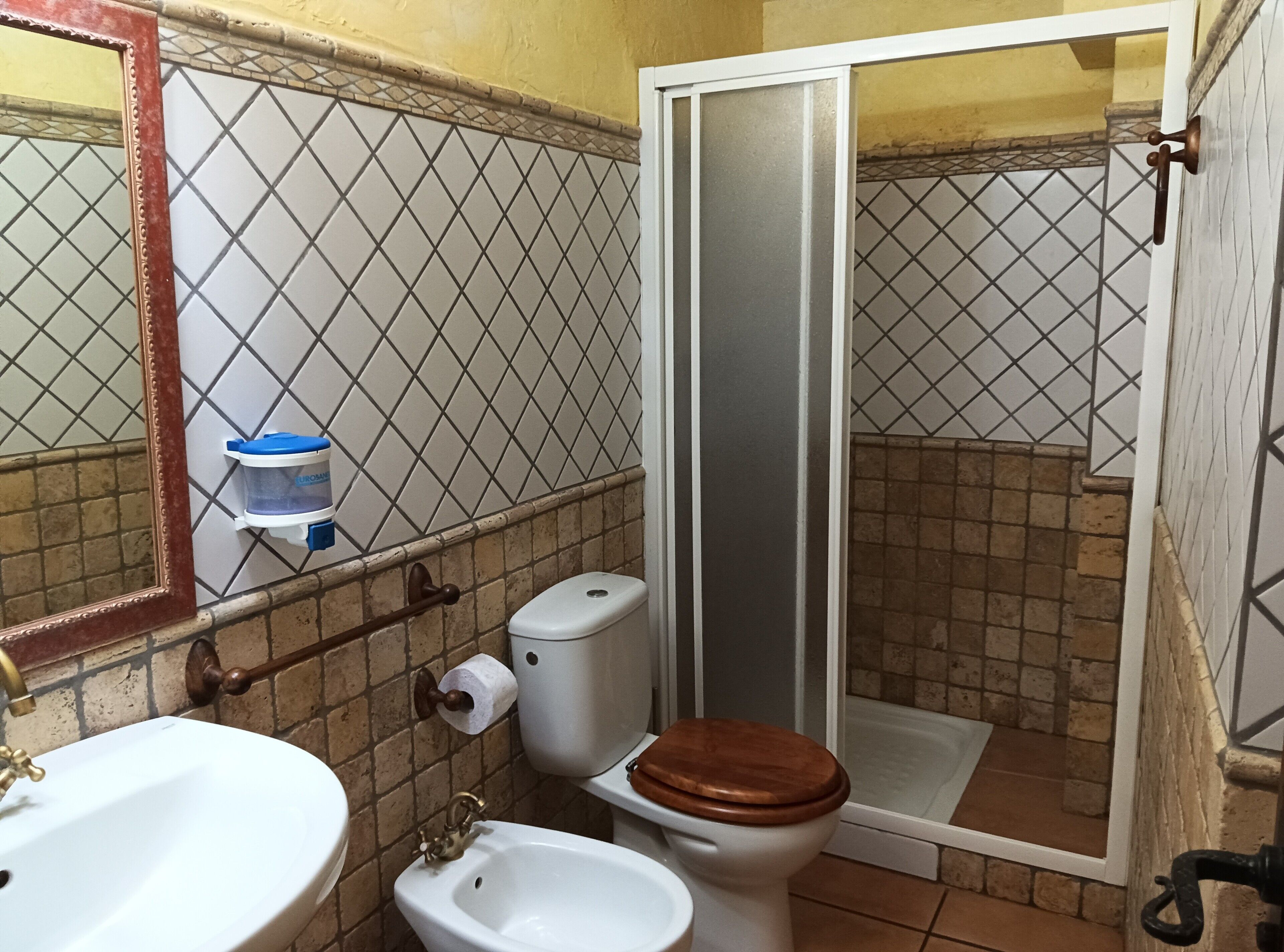 Un baño con inodoro, bidé, lavamanos y ducha.